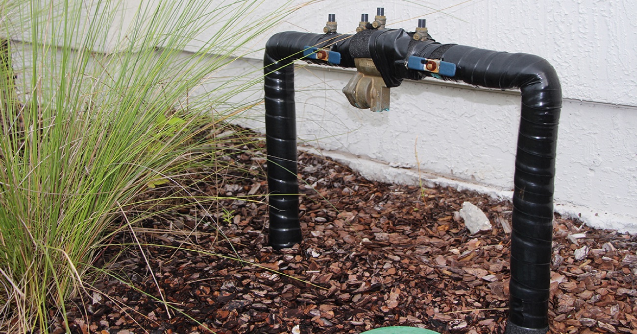 Irrigation backflow preventer wrapped in insulation for freeze protection against a Northeast Florida home