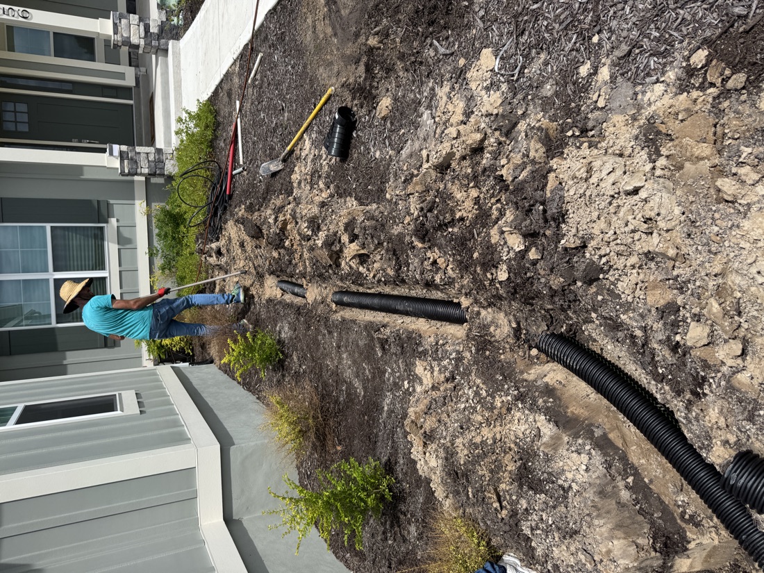 Crew trenching and laying drainage pipe along a Ponte Vedra home