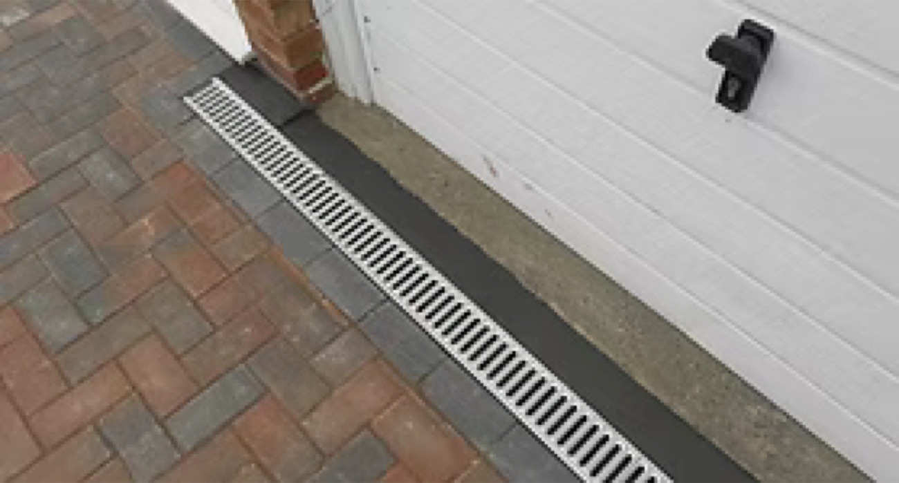 Strip drain set along a driveway edge to capture runoff across a wide area